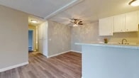 Located at 3971 W Orange Ave in Anaheim, California, this single-floor, 2-bedroom, 1-bathroom unit offers a practical and comfortable layout. Throughout the space, light-toned laminate wood flooring creates a clean, cohesive aesthetic, complemented by neutral gray and beige walls and white trim.

The living room is a bright, open space featuring a ceiling fan with light fixture, a textured ceiling, and a sliding glass door that fills the room with natural light and provides direct access to a landscaped outdoor area with views of mature trees. A wall-mounted A/C unit keeps the space comfortable year-round.

The kitchen is positioned adjacent to the living area, separated by a peninsula breakfast bar with a speckled countertop. White cabinetry provides ample storage, and the layout allows for easy interaction between the kitchen and living spaces. A hallway connects the main living area to the bedrooms and bathroom, with built-in storage cabinetry adding functionality.

Both bedrooms are well-proportioned, featuring laminate flooring, textured ceilings, and windows that bring in natural light. The primary bedroom includes a closet with louvered doors. The bathroom is outfitted with a full tub-shower combination, chrome fixtures, and wood-look flooring, maintaining the consistent style found throughout the unit.