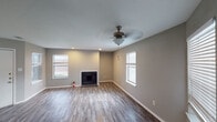 Located at 3502 Curry Ln in Abilene, Texas, this single-story home presents a cohesive, updated interior finished in neutral gray tones throughout. Wood-look plank flooring runs consistently across the living areas, bedrooms, and wet spaces, creating a unified aesthetic.

The main living area is spacious and open, anchored by a classic fireplace and framed by multiple windows with blinds that allow generous natural light. A ceiling fan with a light fixture serves the room, and recessed lighting adds supplemental illumination. The layout extends to a secondary living or dining area equally well-lit by windows and served by the same ceiling fan.

The kitchen features white cabinetry with modern hardware, dark granite-style countertops, a subway tile backsplash, and black appliances including a refrigerator, range, and dishwasher, all beneath recessed lighting.

Bedrooms are well-proportioned with wood-look flooring, window natural light, and closet storage with built-in shelving and hanging rods. The primary bathroom offers a dual-sink vanity with dark countertops, subway tile backsplash, framed mirrors, and a separate shower. A secondary bathroom includes a tub-shower combination with clean white surrounds and matching flooring.