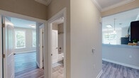 This single-floor residence is designed with a cohesive, contemporary aesthetic carried throughout each space. Warm neutral tones on the walls complement wood-look luxury vinyl plank flooring found across the living and bedroom areas, while light-toned tile floors provide a clean, durable surface in the kitchen and bathrooms.

The kitchen serves as a functional centerpiece, featuring rich dark espresso cabinetry, granite-look countertops, and stainless steel appliances including a range, dishwasher, and refrigerator. A peninsula with pendant lighting and a built-in sink opens toward the living area, enhancing the open flow. A skylight overhead fills the kitchen with natural light.

The bedrooms are well-proportioned, each benefiting from natural light through double- or single-pane windows. One bedroom connects to a spacious walk-in closet outfitted with double-tier wire shelving along multiple walls, offering generous storage capacity.

The primary bathroom features dual vanities with dark cabinetry and granite-look countertops, framed mirrors, and tile flooring, with direct access to the walk-in closet. A secondary full bathroom includes a tub-shower combination, toilet, and additional vanity with matching finishes. Crown molding accents select areas, adding a refined touch throughout.