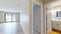 Located at 155 Gleason Lake Rd in Wayzata, MN, this one-bedroom, one-bathroom unit offers a well-organized, efficiently laid-out single-floor living space. The living room is the heart of the home, featuring light hardwood flooring, neutral wall tones, a textured ceiling, and a full-width sliding glass door that opens to a balcony with outdoor views — allowing abundant natural light to fill the room. Baseboard heating and a wall-mounted AC unit ensure year-round comfort.

The kitchen is a standout feature, outfitted with white shaker-style cabinetry, a light gray subway tile backsplash, light countertops, and a full suite of stainless steel appliances including a refrigerator, range, microwave, and dishwasher. Hardwood flooring continues seamlessly from the living area into the kitchen.

The spacious bedroom is carpeted and includes a dedicated closet, a window with blinds offering natural light, and baseboard heating. A hallway with additional closet space connects the main living areas to the full bathroom, which features a tiled tub-shower combination with chrome fixtures. Clean, neutral finishes throughout lend the space a bright and cohesive character.