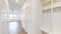 Located at 9549 Glen Rd in Bentonville, AR, this two-story home offers five bedrooms and four bathrooms across two well-proportioned floors. The main level opens into a bright, open-concept living and kitchen area bathed in natural light from front-facing windows. The kitchen is a standout, featuring white shaker cabinetry, a large quartz-topped island with an undermount sink, stainless steel appliances including a French door refrigerator and range, and elegant pendant lighting overhead. Recessed lighting and a ceiling fan complete the inviting living space. Warm wood-look flooring runs consistently throughout both levels, lending cohesion to the clean, modern aesthetic. A built-in mudroom nook near the entry provides practical storage with open shelving and hooks. The upper floor houses the majority of the bedrooms, connected by a hallway and staircase. The generously sized primary bedroom features a ceiling fan and access to a walk-in closet with dual hanging rods and shelving. The primary bathroom is well-appointed with a dual-sink vanity topped in quartz, a round mirror, and a soaking tub with shower. Additional bedrooms are bright and functional, each with ceiling fans and closets. The home's crisp white walls, panel-style doors with brushed nickel hardware, and consistent finishes create a cohesive, move-in-ready feel throughout.