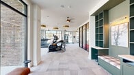 Located at 110 Addison Dr in Athens, Georgia, this modern fitness center is thoughtfully designed to support a comprehensive workout experience. The space is organized across a single floor and divided into distinct functional zones, each catering to different training needs.

The main cardio area features a row of Matrix treadmills and elliptical machines positioned along expansive floor-to-ceiling windows, flooding the space with natural light and offering open outdoor views. Stylish gold drum pendant fixtures and ceiling fans complement the bright, airy atmosphere throughout.

A dedicated strength training zone houses a full rack with free weights, a comprehensive dumbbell rack, adjustable benches, and a cable machine system, all set atop patterned low-pile carpet. Wall-mounted televisions provide entertainment during workouts.

A separate functional training studio, enclosed by sleek steel-framed glass doors, offers a distinct workout environment. This room features warm wood-plank herringbone ceiling detailing, pendant globe lighting, and smooth hardwood-style flooring. It is equipped with TRX suspension trainers, kettlebells, medicine balls, resistance tools, and a plyo box — ideal for dynamic training.

The overall design balances contemporary aesthetics with practical utility, creating an inviting and energizing environment well-suited for a wide range of fitness routines.