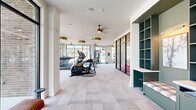 Located at 110 Addison Dr in Athens, Georgia, this modern fitness center is thoughtfully designed to support a comprehensive workout experience. The space is organized across a single floor and divided into distinct functional zones, each catering to different training needs.

The main cardio area features a row of Matrix treadmills and elliptical machines positioned along expansive floor-to-ceiling windows, flooding the space with natural light and offering open outdoor views. Stylish gold drum pendant fixtures and ceiling fans complement the bright, airy atmosphere throughout.

A dedicated strength training zone houses a full rack with free weights, a comprehensive dumbbell rack, adjustable benches, and a cable machine system, all set atop patterned low-pile carpet. Wall-mounted televisions provide entertainment during workouts.

A separate functional training studio, enclosed by sleek steel-framed glass doors, offers a distinct workout environment. This room features warm wood-plank herringbone ceiling detailing, pendant globe lighting, and smooth hardwood-style flooring. It is equipped with TRX suspension trainers, kettlebells, medicine balls, resistance tools, and a plyo box — ideal for dynamic training.

The overall design balances contemporary aesthetics with practical utility, creating an inviting and energizing environment well-suited for a wide range of fitness routines.