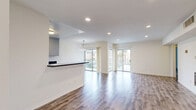 Located on Chenault Street in the sought-after Brentwood neighborhood of Los Angeles, this single-story residence offers a thoughtfully designed layout with one bedroom and five bathrooms. Rich hardwood-style flooring flows throughout the main living areas, creating a warm and cohesive aesthetic.

The open-concept kitchen and living room serve as the heart of the home. The kitchen is well-appointed with gray shaker cabinetry, dark granite countertops, stainless steel appliances including a range, dishwasher, and refrigerator, and a breakfast bar peninsula that connects seamlessly to the living space. Recessed lighting and tile flooring complete the kitchen's clean, modern look.

The living room is expansive and light-filled, boasting multiple sliding glass doors that open to outdoor views of a landscaped courtyard with palm trees, inviting abundant natural light throughout the day. A decorative chandelier adds an elegant touch.

The spacious primary bedroom features mirrored sliding closet doors that maximize storage and amplify the sense of space, along with recessed lighting and access to a well-finished bathroom. The bathrooms are consistently styled with granite countertops, gray cabinetry, framed mirrors, and clean white fixtures, maintaining a unified design language throughout. The entrance and hallway provide smooth transitions between all areas of the home.