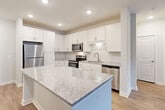 Located at 2465 Richardson Pkwy in Jonesboro, GA, this single-floor residence offers five bedrooms and three bathrooms within a thoughtfully designed layout. The open-concept kitchen serves as the heart of the home, showcasing granite countertop surfaces, a large central island, crisp white shaker cabinetry, a classic subway tile backsplash, and a full suite of stainless steel appliances including a refrigerator, range, microwave, and dishwasher. Recessed lighting illuminates the kitchen and flows into the adjoining living area, which features a ceiling fan and glass doors that invite natural light from outside. Wood-look flooring extends consistently throughout the home, lending a clean, modern aesthetic. The spacious primary bedroom provides a comfortable retreat, while the additional bedrooms are bright and versatile. The bathrooms are finished with granite-topped vanities and wood-look flooring; one features a glass-enclosed walk-in shower, while another includes a soaking tub surrounded by vertically stacked white tile. A dedicated closet with built-in shelving offers generous storage. The utility room and smart thermostat add practical convenience to this well-appointed home.