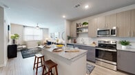 Located at 900 Elm Grove Ave in Gainesville, Georgia, this single-story residence offers a thoughtfully designed open-concept layout with contemporary finishes throughout. Light wood-look flooring flows seamlessly across the living areas, creating a cohesive and inviting atmosphere.

The kitchen serves as the heart of the home, showcasing granite countertops, a generously sized island with bar seating, two-tone cabinetry in light wood and gray, white subway tile backsplash, stainless steel appliances including a refrigerator, range, and microwave, and open shelving for added display space. The kitchen opens directly to the living area, which is brightened by multiple windows fitted with blinds and features a ceiling fan overhead.

The bedroom is a calm retreat with soft blue-gray walls, natural light from a large window, a ceiling fan, and access to a spacious walk-in closet outfitted with wire shelving and multiple hanging rods. The en-suite bathroom includes a granite-topped vanity with gray cabinetry, a soaking tub/shower combination, and clean white tile work.

A dedicated laundry area conveniently houses a full-size side-by-side washer and dryer. Additional storage is provided throughout, and the layout offers both functionality and comfort in a well-appointed, modern setting.