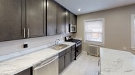 Located at 65 Patton Dr in Bloomfield, NJ, this single-floor unit combines classic architectural character with modern updates throughout. Polished hardwood floors extend across the main living areas and bedrooms, reflecting natural light that streams in through multiple windows dressed with blinds. Classic cast-iron radiators provide warmth and add a timeless quality to each room.

The spacious living area features recessed lighting, neutral gray walls, and clean white baseboards, creating a bright and versatile space. Multiple well-proportioned rooms offer flexible use, each benefiting from natural light and the warmth of the hardwood floors.

The kitchen stands out as a clear highlight, showcasing dark espresso cabinetry that reaches toward the ceiling for ample storage, paired with striking marble-style countertops and a matching island surface. Stainless steel appliances — including a refrigerator, gas range, microwave, and dishwasher — complete this well-appointed space, which also features light tile flooring and a window overlooking the exterior.

The bathroom has been tastefully updated with marble-style wall surround tiles framing a soaking tub and shower combination, a modern white vanity with mirrored medicine cabinet, and polished chrome fixtures, delivering a clean, contemporary aesthetic throughout.
