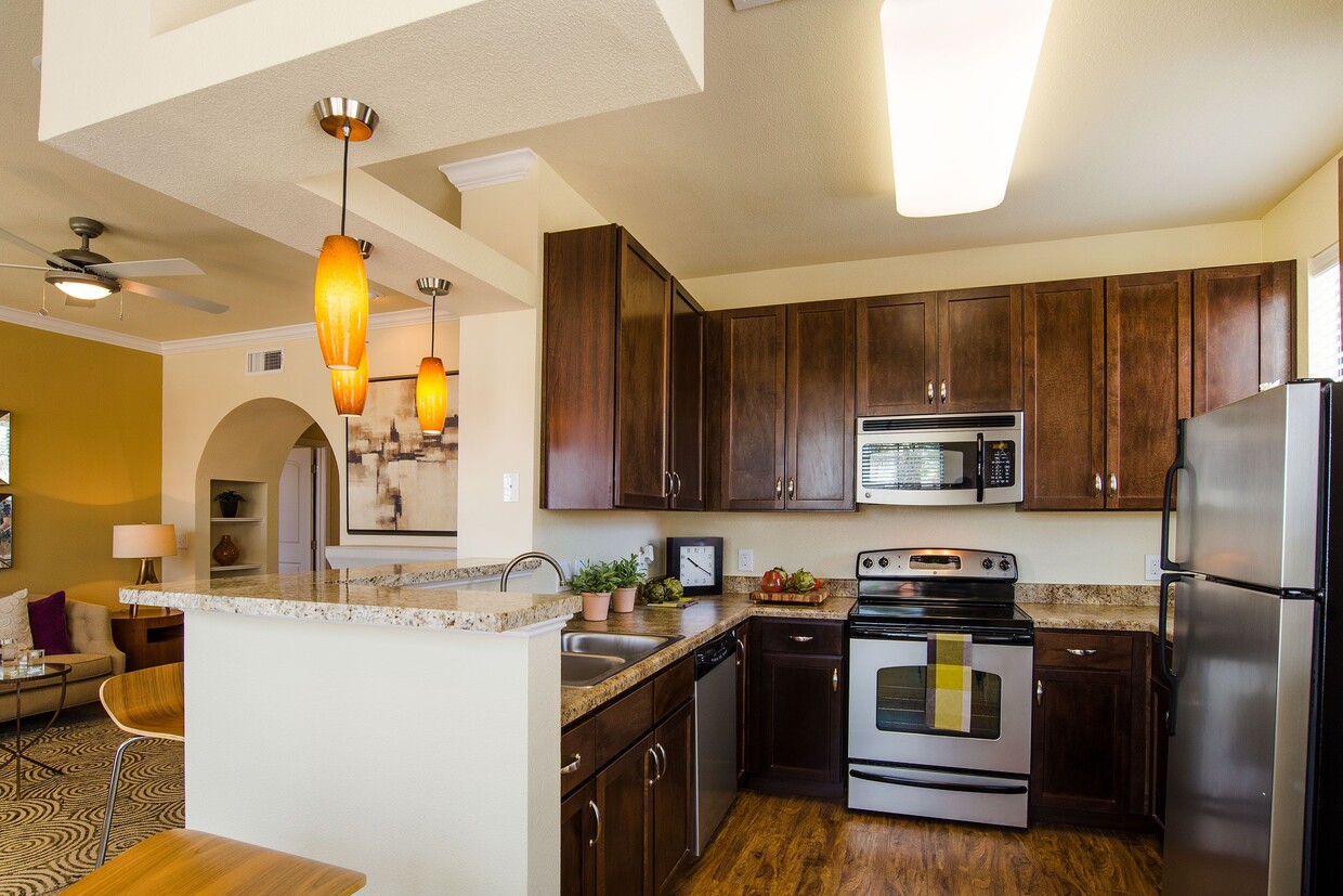 A kitchen with granite counters, dark cabinetry, and stainless steel appliances - Tuscany at Faudree