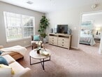 Located at 12910 Dorman Rd in Pineville, NC, this 2-bedroom, 1-bathroom residence offers a thoughtfully designed single-floor layout that maximizes functionality and comfort. The living room serves as the heart of the home, featuring plush carpeting, neutral walls, and a large window that fills the space with natural light and provides views of the outdoor surroundings. The galley-style kitchen is equipped with white cabinetry, granite-look countertops, dark hardwood-style flooring, and black appliances including a range, dishwasher, and refrigerator. The primary bedroom is a comfortable retreat with a window offering outdoor views and soft carpet underfoot. The second bedroom also features carpeting and a double-door closet, providing ample storage. The bathroom includes a tub/shower combination with grab bars and wood-look tile flooring. A hallway connects the main areas, featuring rich hardwood-style flooring and access to multiple closets. A dedicated laundry area adds everyday convenience. Throughout the home, a consistent neutral color palette, clean finishes, and an efficient use of space create a cohesive and welcoming ambiance.