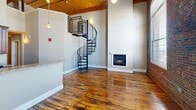 This 1270 square foot apartment in Manchester, NH, offers a blend of historic charm and modern convenience. Spread across two floors of 640 square feet each, the space boasts exposed brick walls, wooden ceilings, and hardwood floors, creating a warm, industrial-chic ambiance. The living area features high ceilings with exposed beams and track lighting, complemented by large windows that flood the space with natural light. A striking spiral staircase connects the two levels, adding visual interest and functionality. The kitchen is equipped with stainless steel appliances, granite countertops, and rich wood cabinetry. The bathroom, though compact, is efficiently designed with a combined tub and shower. Both bedrooms offer ample space, with the primary bedroom measuring 140 square feet. Additional amenities include a fireplace in the living area and multiple closets for storage. The apartment's layout, with its open-plan design and thoughtful use of space, creates a comfortable and stylish urban living environment.