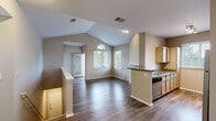 Located at 9003 W Cross Dr in Littleton, Colorado, this single-floor residence offers a well-designed layout that balances openness with defined living spaces. The main living area immediately impresses with soaring vaulted ceilings that amplify the sense of space, complemented by rich hardwood-style flooring throughout. A striking arched window floods the room with natural light, while a glass-paned exterior door provides convenient outdoor access. A gas fireplace anchors one side of the living space, adding warmth and character.

The kitchen is thoughtfully arranged in a galley configuration, featuring light wood cabinetry, dark countertops, and a full suite of stainless steel appliances including a refrigerator, range, and dishwasher. A peninsula with countertop seating connects the kitchen to the main living area, enhancing the open flow.

The bedrooms are carpeted for comfort, each offering natural light through large windows with views of surrounding greenery. Vaulted ceilings continue into the primary bedroom, adding an airy, expansive feel. The bathroom is clean and functional, featuring a tiled tub-shower combination, a light wood vanity, and wood-style flooring. Neutral tones throughout the home create a calm, cohesive aesthetic well-suited to a variety of interior styles.
