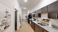 This one-bedroom, one-bathroom residence in Lafayette, Louisiana offers a thoughtfully organized layout that maximizes every inch of its footprint. Light wood-style flooring flows continuously throughout, tying together the home's clean, modern aesthetic.

The galley-style kitchen runs along one wall and is well-appointed with dark espresso cabinetry, granite countertops, a stainless steel sink, and a full suite of black appliances including a range, microwave, and dishwasher. The kitchen opens into a corridor that leads to the bright and comfortable living room, which features crown molding, recessed lighting, and a ceiling fan—creating a polished yet relaxed atmosphere.

The bedroom is a quiet, neutral retreat with light walls, wood flooring, a ceiling fan, and a dedicated walk-in closet outfitted with wire shelving for practical storage.

The bathroom continues the home's modern design language with dark wood cabinetry, granite countertops, a glass-enclosed walk-in shower with white subway tile surround, and light wood flooring.

Crown molding and recessed lighting appear throughout the home, lending a consistent level of refinement to the overall design. The result is a cohesive, functional living space that balances style and practicality in the heart of Lafayette.