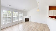 Located at 2260 Golden Garden Circle in Chester, VA, this two-story home offers a well-designed layout across two levels. The main living area is bright and airy, showcasing light hardwood-style flooring, vaulted ceilings, and an abundance of natural light streaming through multiple windows. A corner fireplace serves as a focal point in the living room, complemented by a pendant light fixture that adds a touch of warmth. The open-concept kitchen overlooks the living space through a pass-through counter, featuring white cabinetry, stainless steel appliances including a refrigerator, electric range, and over-the-range microwave, and tile flooring. Carpeted stairs with a warm wood handrail lead to the upper level, where both bedrooms are located. The spacious primary bedroom includes a sliding glass door opening to an outdoor deck, an additional window for natural light, and a closet. The second bedroom is carpeted with a double-door closet. Both bathrooms are finished with tile flooring, white vanities, and tub-shower combinations. The home's clean, neutral palette throughout creates a move-in ready environment that is both functional and inviting.