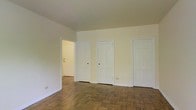 Located at 2907 N High St in Columbus, Ohio's Clintonville neighborhood, this single-floor space offers a clean, functional layout with a timeless interior character. The main room is generously proportioned, featuring classic parquet wood flooring laid in a traditional block pattern that adds warmth and texture underfoot. Neutral white walls and a smooth ceiling create a bright, open atmosphere that is well-suited for a variety of uses. A notable feature of the main room is the arrangement of multiple paneled interior doors along one wall, providing access to additional rooms and storage areas, suggesting a well-organized and versatile floor plan. The six-panel door detailing is consistent throughout, lending a cohesive and classic aesthetic to the interior. White painted trim and baseboards frame the space neatly, complementing the light color palette. The open doorway visible in the corner hints at connected spaces that extend the overall footprint. The overall ambiance is understated and adaptable, with a straightforward design that emphasizes practicality. Situated along the well-traveled North High Street corridor, the location provides convenient access to local dining, shopping, and community amenities characteristic of the Clintonville area.