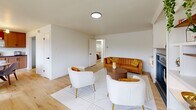 Located in Tacoma's North End neighborhood, this two-story home offers three bedrooms and two bathrooms thoughtfully distributed across two evenly sized floors. The layout provides versatile living arrangements, with separate living spaces on each level connected by staircases and well-planned hallways.

The upper floor features a bright, modern kitchen with warm wood cabinetry, white quartz countertops, stainless steel appliances including a dishwasher and refrigerator, and light hardwood flooring. An adjacent combined dining and living area showcases large sliding windows with leafy outdoor views, a sputnik-style chandelier, and warm-toned wood cabinetry with dark granite countertops. A fireplace with a rich wood mantel and surround serves as a focal point in the main living area.

The lower floor hosts two bedrooms with light wood flooring and windows providing natural light, alongside a cozy secondary living space. The two bathrooms each carry a distinct style: one features dark slate-tiled walls, a soaking tub, and brushed gold fixtures, while the second offers a clean walk-in shower with matte black hardware and gold accents. The home also includes an attached garage and two closets for ample storage.