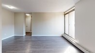 Located on the 9th floor at 235 Rebecca St in Hamilton, Ontario, this 2-bedroom, 2-bathroom unit offers a practical and well-organized layout across a single floor. The combined living and dining area is generously proportioned, featuring dark hardwood-style flooring, neutral-toned walls, a textured ceiling, and a large floor-to-ceiling window that fills the space with natural light and offers city views. A balcony extends the living space outdoors. The kitchen is equipped with white cabinetry, a marble-style countertop, a stainless steel sink, tile backsplash, and tile flooring, with space for a full-size refrigerator. Both bedrooms feature light hardwood-style flooring and large windows that invite abundant natural light and urban views. The primary bedroom includes a double-door closet for ample storage. The unit has two bathrooms: a full bathroom with a tiled tub-shower combination and a second bathroom with tile flooring. Two dedicated closets provide additional storage throughout. A hallway connects the main living areas to the bedrooms and bathrooms, contributing to a functional flow. The overall aesthetic is clean, bright, and neutral throughout.