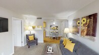 This single-story residence offers a thoughtfully arranged floor plan that balances comfort and functionality across its living spaces. The living room serves as the heart of the home, anchored by a classic brick fireplace and complemented by a sliding glass door that fills the space with natural light and provides access to an outdoor area. Soft carpet and a seamless transition into the dining area create a warm, cohesive atmosphere.

The galley-style kitchen is efficiently designed with light oak cabinetry, white laminate countertops, hardwood-style flooring, and black appliances, including a range and refrigerator. A pass-through connects the kitchen to the dining area, enhancing the open feel between spaces.

The primary bedroom is generously sized, featuring plush carpet, multiple windows for natural light, a mirrored closet, and direct access to a full bathroom. A second bedroom offers comfortable proportions with carpet flooring and ample window light. Two full bathrooms serve the residence, each featuring oak vanity cabinetry, light countertops, and well-lit mirrors. The overall aesthetic is neutral and inviting, with textured ceilings throughout.
