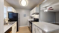 This single-floor, one-bedroom, one-bathroom unit offers a practical and well-organized layout designed to maximize functionality. The open-concept living area is finished with light wood-style flooring and neutral gray walls, creating a clean, cohesive aesthetic throughout. A ceiling fan overhead and a sliding glass door at the far end of the living room allow for natural light and outdoor access, adding an airy quality to the space. A pass-through counter connects the living area to the kitchen, maintaining visual openness between the two zones.

The galley-style kitchen is efficiently arranged with white cabinetry lining both sides, providing ample storage above and below the counters. Light granite-style countertops contrast cleanly with the black and stainless steel appliances, which include a refrigerator, electric range with overhead ventilation, and dishwasher. Light wood flooring continues from the living area into the kitchen, maintaining a consistent flow.

The bedroom is a generously sized private retreat, carpeted for comfort and finished with the same neutral gray tones found throughout the unit. A window fitted with blinds allows for natural light while maintaining privacy. A textured ceiling is present throughout the entire unit, adding a subtle layer of dimension to each room.