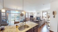 This thoughtfully designed single-floor residence offers a seamless open-concept layout that connects the kitchen, dining, and living areas into one cohesive and functional space. The kitchen is outfitted with rich dark cabinetry, granite countertops, a large island with an undermount sink, and a full suite of stainless steel appliances, including a refrigerator, range, and over-the-range microwave. Hardwood flooring flows throughout the main living areas, adding warmth and continuity.

The living room serves as the heart of the home, anchored by a tile-surround fireplace and framed by multiple windows that invite abundant natural light and outdoor views. A dedicated den or flex room provides additional living space, featuring its own windows and a cozy, relaxed atmosphere.

The primary bedroom is generously proportioned with plush carpeting, a large window with exterior views, and direct access to an en-suite bathroom. The primary bath includes a dark-cabinet vanity with a granite-style countertop and leads to a spacious walk-in closet. A second full bathroom mirrors the finishes of the primary and serves additional bedrooms or guests. A versatile bonus room with a daybed offers flexible use as a guest space or office.