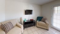 Located at 3800 Michael Blvd in Mobile, Alabama, this single-floor residence offers a practical and comfortable layout designed for everyday living. The open living area features light tile flooring and neutral walls, providing a bright and welcoming atmosphere. A wall-mounted flat-screen TV, seating arrangements, and warm accent lighting give the space a relaxed, functional character.

The kitchen is outfitted with warm oak cabinetry offering generous storage, a double-basin stainless steel sink, a coil-top electric range, and a white dishwasher. Light tile flooring and laminate countertops complete the clean, utilitarian aesthetic.

The bedrooms are carpeted and fitted with ceiling fans, creating a cozy retreat. Each room benefits from natural light through window blinds and provides ample space for standard furnishings.

The bathrooms feature white tile surrounds with a tub-shower combination, a wide vanity countertop with an undermount sink, and a large wall mirror that enhances the sense of space.

A dedicated laundry area houses a full-size Whirlpool washer and dryer set with overhead wire shelving for additional storage, adding significant convenience to the home. Overall, this residence combines practical amenities with a clean, understated design throughout.