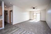 This single-floor unit offers a practical and well-organized layout across a comfortable footprint. The open-concept living and dining area serves as the central gathering space, featuring a combination of light wood-style laminate flooring and plush carpeting. A ceiling fan overhead provides airflow, while a sliding glass door with vertical blinds leads to a private balcony, filling the space with natural light and offering outdoor views.

The galley-style kitchen is positioned adjacent to the living area and is equipped with warm-toned oak cabinetry, white appliances including an electric range and refrigerator, light countertops, and a built-in sink. The layout maximizes efficiency within the available space.

The bedrooms are carpeted and well-lit, with multiple windows fitted with blinds that allow for ample natural light. One bedroom features a walk-in closet outfitted with built-in shelving and dual hanging rods, offering generous storage capacity.

The unit includes two bathrooms: a full bath with a tub-shower combination enclosed by sliding frosted glass doors, and a second bathroom with a vanity, toilet, and wood-style flooring. Both bathrooms feature oak cabinetry and light countertops, maintaining a consistent design throughout the unit.