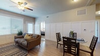 This single-floor unit is thoughtfully designed with a cohesive aesthetic that combines modern finishes with classic architectural details. Throughout the main living areas, light hardwood-style flooring creates a warm, clean foundation, while board-and-batten wainscoting lining the walls adds a refined, decorative touch that carries consistently through the living, dining, and bedroom spaces.

The living room is bright and welcoming, featuring a ceiling fan, large windows that admit generous natural light, and direct access to an exterior door. It flows seamlessly into the dining area, which comfortably accommodates a full dining set and sits adjacent to the kitchen. The kitchen is well-equipped with dark espresso cabinetry, granite countertops, black appliances, recessed lighting, and a peninsula with a sink—offering both functional workspace and visual contrast.

The bedrooms are carpeted for comfort and feature large windows with outdoor views and continued wainscoting detail. Both bathrooms mirror the kitchen's design language, each offering granite-topped vanities with stylish cabinetry and a tub-shower combination. A dedicated laundry room with a full-size washer and dryer rounds out the practical amenities of this well-appointed space.