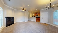 Located at 5455 Rowley Rd in San Antonio, TX, this 2-bedroom, 2-bathroom single-floor residence offers a thoughtfully designed layout with comfortable living spaces throughout. The open-concept living and dining area serves as the heart of the home, featuring plush carpeting, crown molding, recessed lighting, and a ceiling fan. A sleek black fireplace anchors the living room, while arched windows allow natural light to fill the space. The dining area is distinguished by elegant bay-style arched windows, a chandelier, and direct access to a private balcony. The kitchen is well-appointed with warm wood cabinetry, dark granite countertops, wood-look tile flooring, and stainless steel appliances, complemented by a pantry for additional storage. The primary bedroom offers a generous footprint with plush carpet, crown molding, a ceiling fan, and a walk-in closet. The second bedroom also features carpet flooring, a ceiling fan, and a window for natural light. Both bathrooms include wood-look tile flooring and warm wood vanities. A dedicated laundry area and utility room add convenience. With four closets and an efficient single-level floor plan, this home provides ample storage and functional living throughout.