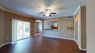 Located at 29th Way N in Pinellas Park, Florida, this single-floor residence offers a thoughtfully designed open-concept layout that promotes a seamless flow between living spaces. The expansive living and dining area is finished with rich, dark hardwood flooring and is accented by crown molding and a ceiling fan with light fixture. A sliding glass door opens to an outdoor balcony, allowing natural light to fill the space. An elegant arched pass-through connects the living area to the kitchen, which features white cabinetry, dark granite-style countertops, stainless steel appliances including a refrigerator and range, a double-basin sink, and tile flooring. Track lighting illuminates the kitchen efficiently. The bedroom features neutral-toned carpet and ample wall space, providing a calm and functional retreat. Two full bathrooms are present in the unit; one includes a tiled tub-and-shower combination with a white vanity and stone-top countertop, while the other offers a clean, white tub-shower surround with matching white cabinetry. Both bathrooms continue the warm neutral color palette found throughout the residence, creating a cohesive and comfortable living environment.