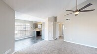 Located at 1500 Plantation Oaks Drive in Westlake, TX, this single-story 2-bedroom, 2-bathroom home offers a well-designed layout with a cohesive neutral palette throughout. The living room makes a strong first impression with soaring vaulted ceilings, a ceiling fan, a tile-surround fireplace, and built-in shelving flanking the entryway. Large windows with white blinds invite natural light into the space, which transitions from dark tile flooring near the entry to plush carpeting in the main living area. The kitchen is thoughtfully appointed with gray cabinetry, a subway tile backsplash, white countertops, dark tile flooring, and stainless steel appliances including a range, microwave, and dishwasher. A window above the sink adds natural light to the workspace. The spacious primary bedroom features vaulted ceilings, a ceiling fan, soft carpet, and direct access to its own en-suite bathroom. The second bedroom is equally comfortable with carpet and a ceiling fan. Both bathrooms are finished with gray vanity cabinetry, white countertops, dark tile flooring, and tub-shower combinations accented with gray subway tile. A hallway connects the bedrooms and includes two closets for ample storage.