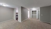 This single-floor unit offers a practical and comfortable layout designed for everyday living. The spacious living area is finished with neutral carpet and soft gray walls, creating a calm, versatile backdrop for any style of furnishing. A large sliding glass door floods the room with natural light and provides a pleasant view of the surrounding greenery, enhancing the open, airy feel of the space.

The kitchen is efficiently designed with white cabinetry, granite countertops, and stainless steel appliances including a refrigerator and dishwasher. Dark hardwood-style flooring in the kitchen and hallway provides a clean contrast to the carpeted living areas and adds a touch of warmth to the overall aesthetic.

The bathroom is well-appointed with a granite-topped vanity, white cabinetry, a large wall mirror, and a combined tub and shower enclosure with tile surround. Dark hardwood-style flooring continues here, complementing the neutral gray walls throughout.

Additional highlights include a dedicated closet area with bifold doors, offering ample storage. The unit's cohesive color palette of gray tones and white trim ties the spaces together, resulting in a clean, modern, and move-in-ready interior.