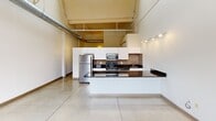 Located at 1900 E Superior Ave in Cleveland, OH, this single-floor loft blends industrial character with modern finishes in a compact yet efficient layout. The open main living area makes an immediate impression with its soaring ceilings, exposed ductwork, and dramatic arched windows set into original brick walls. Large-format tile flooring and abundant natural light enhance the sense of openness throughout the space.

The kitchen is a standout feature, designed with a sleek, contemporary aesthetic. It includes white cabinetry extending to the ceiling, dark granite countertops, stainless steel appliances, and a mosaic tile backsplash that adds texture and warmth. A peninsula provides additional counter space and separates the kitchen from the main living area, while track lighting overhead ensures excellent task illumination. The high ceilings in this area also reveal exposed industrial piping, reinforcing the loft's urban character.

The bathroom is well-appointed with warm terracotta floor tiles, a white vanity topped with granite, a full bathtub and shower with mosaic tile accents, and clean white walls that keep the space feeling bright and functional.

Overall, this loft offers a distinctive urban living experience, combining the raw architectural heritage of a converted industrial building with thoughtfully chosen modern upgrades.