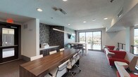 Located at 1930 Kingsley Dr in Pearland, Texas, this single-floor community clubhouse and leasing facility offers a well-appointed, multifunctional space designed for both productivity and relaxation. The interior is finished with plush patterned carpeting and recessed lighting throughout, creating a bright and welcoming atmosphere.

The open main area serves as both a leasing office and lounge, featuring a large communal work table with white ergonomic chairs, individual workstations equipped with computers, and a comfortable seating arrangement with bold red and white upholstered chairs. Decorative textured wall panels and geometric-patterned accent walls add visual depth and a modern aesthetic.

A dedicated gathering and collaboration zone includes a raised bar-height table with dark barstools, a wall-mounted flat-screen TV, and large sliding glass doors that flood the space with natural light and offer direct views of the outdoor pool and surrounding residential community. The pool-view vantage point creates a seamless indoor-outdoor connection.

Additional functional amenities include a printer and office equipment station with built-in cabinetry, a designated WiFi zone, and clearly defined entry points with modern gray-paneled doors. The space also features a railed interior transition area with a stylish stacked-wood accent wall, adding warmth to the contemporary design. Overall, the space balances professional utility with comfortable community living.
