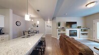 Located at 2271 E Dinosaur Crossing Dr in St. George, Utah, this well-appointed one-bedroom, one-bathroom unit offers a thoughtfully designed single-floor layout. The open-concept living, dining, and kitchen area creates a seamless flow throughout the main space. The kitchen is outfitted with white shaker cabinetry, granite countertops, stainless steel appliances including a gas range and full-size refrigerator, and a breakfast bar with barstool seating. Pendant lighting accents the kitchen island, while a dedicated dining area features a chandelier overhead. The living room provides a comfortable gathering space anchored by a built-in fireplace with shelving, wood-look flooring, and a window for natural light. The bedroom offers plush carpet, direct access to a closet, and a connecting doorway to the full bathroom, which includes a granite-topped vanity and a full tub/shower combo. A dedicated laundry room with full-size washer and dryer hookups adds everyday convenience. Neutral tones and consistent finishes throughout give the space a clean, cohesive aesthetic suited for comfortable living in sunny southern Utah.