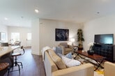 This single-floor residence is thoughtfully designed with an open-concept layout that promotes a natural flow between living spaces. The kitchen serves as a central hub, showcasing rich dark-brown cabinetry, stainless steel appliances, a granite-topped island with bar seating, and a deep undermount sink — all set above durable hardwood-style flooring that extends throughout the main living areas. Recessed lighting illuminates the space, complementing the natural light admitted through multiple windows.

The living room is generously proportioned, featuring neutral walls and hardwood-style flooring that create a warm, inviting atmosphere. A dedicated study or flex room provides a quieter retreat, equipped with built-in bookshelves and a workspace area, finished with a large area rug atop the same wood flooring.

The bedrooms offer a distinct contrast with plush carpeting underfoot, ceiling fans for added comfort, and windows that bring in soft natural light. Clean white walls and ample floor space give each room a calm, airy quality. The bathroom features a glass-enclosed walk-in shower with tiled walls and chrome fixtures, maintaining the residence's consistent modern aesthetic throughout.