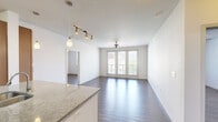 Located at 2604 Aldrich St in Austin's 78723 zip code, this two-bedroom, two-bathroom residence offers a well-designed single-level floor plan with a functional and modern aesthetic. Rich hardwood-style flooring runs throughout the entire unit, lending warmth and visual continuity across every room.

The open-concept kitchen and living area serves as the heart of the home. The kitchen features warm-toned wood cabinetry extending to the ceiling for ample storage, granite countertops, stainless steel appliances including a refrigerator, microwave, and range, and a peninsula island with a double sink and pendant lighting overhead.

The spacious primary bedroom offers access to a private balcony through large glass doors, filling the room with natural light and outdoor views of the surrounding Austin landscape. The second bedroom is equally bright, featuring a window with natural light and a ceiling fan. Both rooms are generously proportioned with dedicated closets, including a walk-in closet equipped with wire shelving systems for organized storage.

Each of the two bathrooms is finished with warm wood vanity cabinetry, light countertops, a large mirror, and overhead vanity lighting. Ceiling fans are present throughout the living areas and bedrooms, ensuring comfortable airflow year-round. A connecting hallway ties all spaces together in a coherent, easy-to-navigate layout.