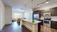 Located along East Speer Boulevard in Denver's vibrant Golden Triangle neighborhood, this well-appointed one-bedroom, one-bathroom residence offers a thoughtfully designed open-concept layout. The kitchen serves as the centerpiece of the living space, showcasing a large granite-topped island with pendant lighting, dark espresso cabinetry, stainless steel appliances including a French door refrigerator, and a classic subway tile backsplash. Rich hardwood flooring extends throughout the main living areas, complemented by track lighting that keeps the space bright and modern. In-unit stacked washer and dryer add everyday convenience. The living room is bathed in natural light through a wide bank of windows framing city views, while the spacious bedroom features plush carpeting, soaring ceilings, a ceiling fan, and expansive windows overlooking the Denver skyline. A generous walk-in closet with multi-level wire shelving provides ample storage. The bathroom is finished with large-format tile flooring, a bold cobalt blue vanity, a wide mirrored vanity, and a deep soaking tub with tiled surround. A connecting hallway ties all rooms together for a seamless and functional flow throughout this well-designed urban residence.