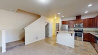 This well-designed three-floor home offers generous living space distributed thoughtfully across its three levels. The ground floor houses an attached garage with drywall-finished walls and an automatic opener, providing secure and convenient parking or additional storage. The main living level features an open-concept kitchen and living room, where rich cherry wood cabinetry, stainless steel appliances — including a refrigerator, range, and microwave — and a tile countertop breakfast bar create a functional and inviting space. Tile flooring flows through the kitchen, transitioning to carpet in the living area, while recessed lighting and multiple windows fill the space with natural light and views of surrounding greenery. A staircase connects all three levels with ease. The upper floor hosts all three bedrooms, including a spacious primary bedroom with a well-appointed en-suite bathroom featuring a walk-in glass shower, soaking tub, tile flooring, and a windowed layout for natural brightness. Additional bedrooms are carpeted and offer windows with views of the outdoors. Walk-in closets equipped with wire shelving systems provide ample storage. A dedicated laundry room on the upper floor includes a full-size washer and dryer with overhead shelving. With four bathrooms total, this home delivers comfort and practicality throughout.