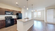 This 2-bedroom, 2-bathroom residence in Austin, TX offers a thoughtfully designed single-level layout that maximizes functionality and comfort. The open-concept kitchen serves as the heart of the home, showcasing rich dark-wood cabinetry, granite countertops, a central island with a built-in sink, and stylish pendant lighting overhead. Black appliances, including a refrigerator and range, complement the kitchen's classic aesthetic, while a large pantry with double doors provides ample storage. Wood-style flooring flows throughout the kitchen and living areas, leading to a bright, airy living room with a ceiling fan and multiple windows that invite generous natural light.

Both bedrooms are carpeted and feature ceiling fans, with the primary bedroom offering elevated windows for added privacy and a walk-in closet. The second bedroom is equally comfortable, with a large window framing outdoor views. Each bathroom is well-equipped with dark-wood vanities, light countertops, large mirrors with overhead lighting, and wood-style flooring. The primary bathroom includes direct access to the bedroom, creating a convenient en-suite feel. Overall, the residence presents a clean, modern aesthetic with consistent finishes throughout.