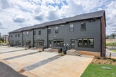 Northside Townes 507 is a well-appointed three-bedroom, three-bathroom townhome in Spartanburg, SC, offering 1,540 square feet of living space spread across three floors. The ground floor (250 sq ft) features a bright entry with large windows and a glass-panel door that floods the space with natural light and provides outdoor views of the community. The main living level (690 sq ft) showcases an open-concept kitchen and living area with durable wood-look flooring throughout. The kitchen is equipped with rich dark cabinetry, granite countertops, stainless steel appliances, a center island with built-in shelving, and recessed lighting. The living area includes a ceiling fan and additional windows. The upper floor (600 sq ft) houses the bedrooms, including a primary suite of 160 sq ft with a ceiling fan, private ensuite bathroom featuring granite countertops and dark cabinetry, and a spacious walk-in closet with wire shelving. The additional bedrooms are well-sized with easy hallway access. All three bathrooms include tub-shower combos with built-in shelving. A dedicated laundry room with Samsung washer and dryer completes the upper level.
