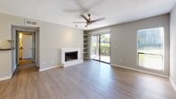 Located at 1850 Ashley Crossing Ln, Unit 8B in Charleston, SC, this single-floor residence offers a well-organized layout with a clean, neutral aesthetic throughout. The living room serves as the central gathering space, highlighted by a classic white brick fireplace, built-in shelving, a ceiling fan, and light wood-look flooring. Sliding glass doors open directly to an outdoor area, filling the room with natural light and providing views of lush greenery. Adjacent to the living room, a dedicated dining area features the same wood-look flooring and connects seamlessly to the kitchen, which is equipped with stainless steel appliances — including a gas range and refrigerator — white cabinetry, subway tile backsplash, and dark granite-style countertops. The bedroom is carpeted for comfort, includes a walk-in closet, and also features sliding glass doors that open to the outdoors. A ceiling fan adds to the room's functionality. The bathroom is finished with wood-look tile flooring, white cabinetry with dark countertops, and a full tub-shower combination. The textured ceilings and consistent neutral color palette create a cohesive, move-in-ready environment throughout the home.