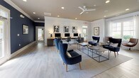 Located at 1500 Parklawn Dr in Charleston, SC, this single-floor community clubhouse offers a well-appointed gathering space designed with a modern coastal aesthetic. White shiplap walls, light wood-look tile flooring, and recessed lighting create a bright, welcoming atmosphere throughout. The open-concept layout flows seamlessly between distinct functional zones.

The lounge area is furnished with plush navy velvet wingback chairs and accent seating arranged around coffee tables, complemented by ceiling fans and framed artwork. Adjacent to the lounge is a game room featuring a full-size pool table, a comfortable gray sofa, and green velvet accent chairs beneath a statement chandelier, with a mounted flat-screen TV on the shiplap wall.

A central bar and kitchen area serves as a visual anchor, highlighted by a bold navy island with dark countertops, a rich wood-clad column, pendant lighting, and bar stool seating. Open shelving, a flat-screen TV, and a beverage station complete this social hub.

The business center offers a dedicated row of desktop computer workstations along the wall, paired with stylish seating for informal meetings or individual work. A separate reception area features exposed dark wood ceiling beams, a curved white reception desk, hardwood flooring, and abundant natural light from large surrounding windows.