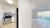 Located at 850 W 49th St in Hialeah, FL, this one-bedroom, one-bathroom unit offers a bright and functional layout finished entirely in light-toned ceramic tile flooring. The living area is open and airy, filled with natural light streaming through a full-width sliding glass door fitted with vertical blinds that opens to a private balcony with outdoor views of the surrounding neighborhood and lush palm trees. A chandelier overhead adds a subtle decorative touch to the space.

The kitchen is positioned adjacent to the living and dining area, connected via a pass-through window that keeps the layout open and communicative. It features white cabinetry, a black refrigerator, and an electric range, providing essential functionality in a compact footprint.

The bedroom is a comfortable, well-proportioned retreat with large windows that invite generous natural light and frame views of the palm-lined surroundings. A dedicated closet provides convenient storage.

The bathroom is clean and well-appointed, featuring a tub-shower combination with gold-toned fixtures, a vanity with storage, and white tile throughout. A hallway connects the rooms efficiently, completing the well-organized floor plan. The unit's consistent white walls and tile flooring create a cohesive, clean aesthetic throughout.
