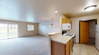 Located at 1951 Scheuring Rd in De Pere, Wisconsin, this single-floor, two-bedroom, one-bathroom home offers a practical and comfortable layout with a generous amount of living space. The open-concept kitchen and living area serves as the heart of the home, where light-toned carpeting flows into the living room and tile flooring defines the kitchen. The kitchen is equipped with oak cabinetry, a white electric range, built-in microwave, and a peninsula counter that separates it from the living area, which features a decorative chandelier and a sliding glass door that provides natural light and outdoor access. An in-unit washer and dryer hookup area is conveniently accessible from the kitchen corridor. The spacious primary bedroom is a standout feature, offering generous proportions, plush carpeting, a window with natural light, and access to a well-appointed walk-in closet with built-in shelving and hanging rods. The second bedroom is also comfortably sized with carpeting and baseboard heating. The full bathroom features tile flooring, oak vanity cabinetry, a large mirror, and a tub/shower combination. Throughout the home, warm oak wood trim, neutral wall tones, and baseboard heating create a cohesive and functional living environment.