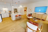 This contemporary 750 square foot apartment in Irvine, CA, offers a harmonious blend of style and functionality. The open-concept design seamlessly integrates the living, dining, and kitchen areas, creating a spacious feel. The single bedroom, measuring 150 square feet, provides a cozy retreat with large windows allowing ample natural light.

The kitchen impresses with its sleek white cabinetry, stainless steel appliances, and a convenient island with seating. The living room features a comfortable seating area, a large TV, and floor-to-ceiling windows that flood the space with sunlight. A charming dining nook with a round table and unique lighting adds character to the apartment.

Two well-appointed bathrooms offer modern fixtures and ample storage. Light wood flooring throughout enhances the bright, airy ambiance. The apartment's decor showcases a neutral palette accented with pops of warm colors, creating a welcoming atmosphere. Thoughtful touches like potted plants and stylish furnishings complete this sophisticated urban dwelling, perfect for those seeking a turn-key, low-maintenance lifestyle in a prime Irvine location.