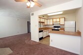 This single-floor residence at 340 N College Dr in Franklin, Virginia offers a practical and functional layout with a welcoming open-concept design. The spacious living area is finished with wall-to-wall carpet and features a ceiling fan overhead, providing comfortable airflow throughout. Large windows and a glass-paned exterior door allow natural light to fill the room while offering views of the outdoors.

The kitchen is efficiently arranged in an L-shaped configuration, featuring white cabinetry with warm wood trim, laminate countertops, a double-basin sink, and a freestanding electric range. A pass-through opening connects the kitchen to the living space, enhancing the open feel of the floor plan.

The bedrooms are generously sized, each carpeted and bright, with one bedroom offering a wide closet with a hanging rod for ample storage. The bathroom is cleanly appointed with tile flooring, a single-sink vanity with a mirrored medicine cabinet, and a full soaking tub with a shower surround. A hallway connects the private areas of the home, with additional closet space visible along the corridor. The overall layout is straightforward and well-organized, making this a functional and accessible single-floor living space.