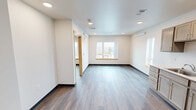 Located at 1120 S 11th St in Tacoma, Washington, this one-bedroom, one-bathroom unit offers a practical and well-designed single-floor layout. The interior features durable wood-look flooring throughout, crisp white walls, and recessed lighting that lend a clean, modern aesthetic to the space.

The open kitchen is equipped with light wood cabinetry offering generous storage, a white electric range, refrigerator, and a single-basin sink with a window nearby. The layout allows for easy movement and functionality. Adjacent to the kitchen, the living room provides a comfortable open area filled with natural light from multiple windows that frame views of the surrounding Tacoma cityscape.

The bedroom is a well-proportioned private retreat featuring a large window with an urban view, a wall-mounted climate control unit, and recessed lighting. A dedicated closet provides convenient built-in storage.

The bathroom is finished in a clean, all-white palette and includes a full soaking tub with shower, a toilet, and a single vanity with a quartz-style countertop and mirror. The tile flooring completes the tidy, functional design.

Overall, this unit presents a straightforward and efficiently organized living space with consistent finishes, ample natural light, and a neutral color scheme throughout.