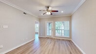 This single-story, 2-bedroom, 2-bathroom home offers a thoughtfully designed layout with consistent, high-quality finishes throughout. The open living room serves as the heart of the home, featuring light hardwood-style flooring, crown molding, recessed lighting, and a ceiling fan. Large windows and a glass exterior door flood the space with natural light and provide views of lush greenery outside. The kitchen is equipped with white cabinetry, granite countertops, subway tile backsplash, and a full suite of stainless steel appliances, including a side-by-side refrigerator, range, and over-the-range microwave, all set on clean tile flooring. The spacious primary bedroom continues the hardwood-style flooring and features a ceiling fan, ample natural light, and direct access to the primary bathroom, which boasts a dual-sink vanity with granite countertops. The second bedroom is generously sized with large windows offering garden views and its own ceiling fan. A second full bathroom mirrors the same granite vanity finishes. The dedicated in-unit laundry room houses a full-size washer and dryer with built-in shelving above, adding excellent everyday convenience. A closet provides additional storage throughout this efficiently designed home.