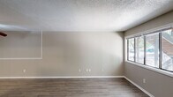 This single-story home in Columbia, SC offers a practical and well-organized layout across four bedrooms and two full bathrooms. The combined kitchen and living room serves as the heart of the home, with the living area featuring durable wood-look flooring, neutral beige walls, textured ceilings, and a large window that invites natural light and outdoor views. A ceiling fan enhances comfort in the adjoining space. The galley-style kitchen is equipped with white cabinetry, granite-look countertops, a stainless steel double sink, and white appliances including a range and refrigerator, all set above matching wood-look flooring. The four bedrooms offer a mix of wood-look and carpeted flooring, with neutral toned walls and textured ceilings throughout. Several bedrooms include closets — five in total across the unit — providing generous storage. Windows in the bedrooms frame views of mature trees, adding a natural element to the interior. Both bathrooms feature tub-shower combinations with white tile surrounds and chrome fixtures. A central hallway connects the living spaces to the bedrooms and bathrooms, contributing to an efficient and cohesive floor plan. The overall ambiance is clean, understated, and move-in ready.