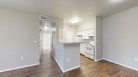 This single-story, 2-bedroom, 2-bathroom residence offers a practical and comfortable layout designed to maximize functionality. The open-concept living, dining, and kitchen area serves as the heart of the home, featuring rich wood-look flooring throughout and neutral gray walls that create a clean, cohesive aesthetic. The living room receives natural light through a large window and a glass-panel exterior door, lending the space a bright and welcoming feel.

The galley-style kitchen is outfitted with white cabinetry, light stone-look countertops, and white appliances, including a refrigerator and electric range. A peninsula counter separates the kitchen from the main living area, providing additional prep space and a natural division between zones. A dedicated pantry offers extra storage, and a hallway connects the living area to the private quarters.

Both bedrooms are carpeted and bathed in natural light, with the primary bedroom featuring a walk-in closet equipped with wire shelving. The second bedroom also benefits from a windowed view and generous closet access. In total, the unit includes four closets, ensuring abundant storage throughout.

The two bathrooms are finished with wood-look flooring, white vanity cabinetry, stone-look countertops, and a tub-shower combination, maintaining the home's consistent, clean design palette.
