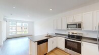 Located at 268 Market St in South Burlington, Vermont, this one-bedroom, one-bathroom residence offers a thoughtfully designed, efficient layout with clean, modern finishes throughout. Light hardwood flooring flows seamlessly across the entire space, creating a bright and cohesive aesthetic.

The open-concept kitchen and living area serves as the heart of the home. The kitchen features white shaker-style cabinetry, dark granite-style countertops, and a full suite of stainless steel appliances, including a refrigerator, electric range, built-in microwave, and dishwasher. A peninsula with an integrated sink provides additional prep space and doubles as a casual dining area.

The living area benefits from large windows that invite generous natural light and offer views of the surrounding neighborhood. A wall-mounted mini-split system provides efficient climate control, complemented by baseboard heating units along the exterior walls.

The bedroom is a well-proportioned retreat featuring a large window with neighborhood views and a double closet offering ample storage. The bathroom is clean and functional, with white cabinetry, a white countertop vanity, and a walk-in shower stall with built-in shelving. Recessed lighting throughout adds a polished, contemporary touch to this move-in-ready residence.
